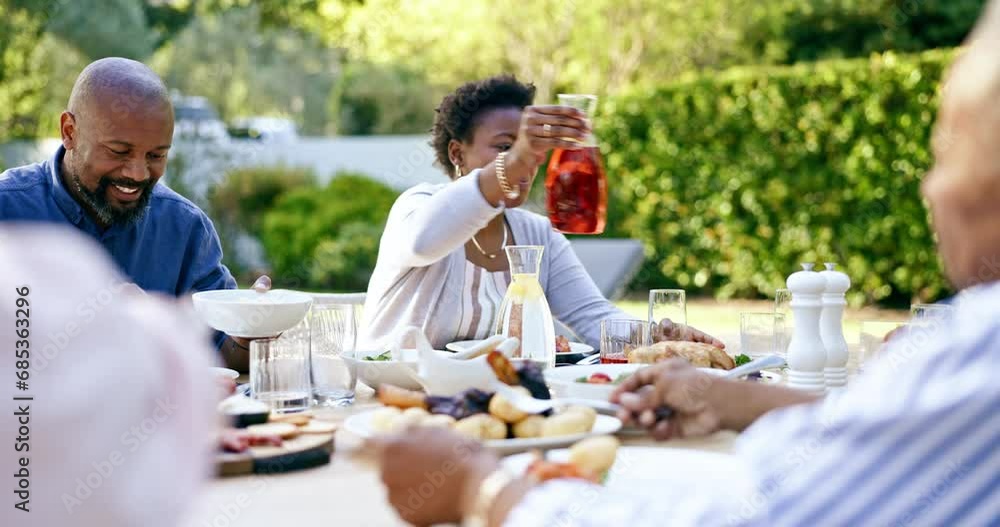 Family, lunch and talking in garden, drink and food to relax in conversation at thanksgiving holiday. Black woman, African man and giving juice with salad, meat or care at event, party or brunch Family, lunch and talking in garden, drink and food to relax in conversation at thanksgiving holiday. Black woman, African man and giving juice with salad, meat or care at event, party or brunch