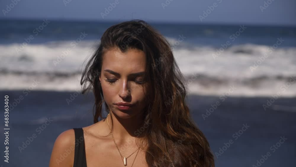 Beautiful brunette woman eating piece of meat on black beach location Beautiful brunette woman eating piece of meat on black beach location
