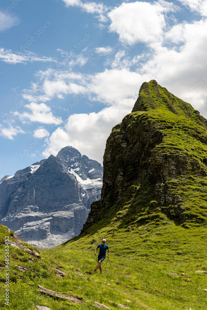 Trailrunning in den Schweizer Alpen - Ein Trailrunner meistert mit Leichtigkeit und Geschwindigkeit die satten, grünen Wege der Schweizer Alpen, umgeben von atemberaubenden Gipfeln - Wetterhorn