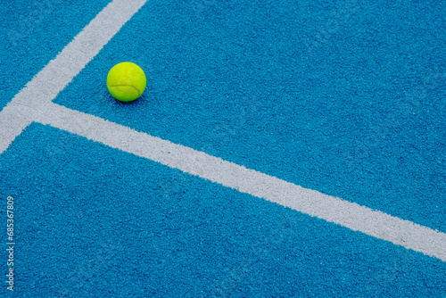 blue paddle tennis court with a ball on the surface, racket sports courts concept © Vic