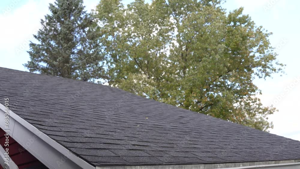 Light hail falls down an asphalt rooftop during a fall day. Light hail falls down an asphalt rooftop during a fall day.