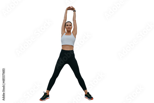 Purposeful sporty multi ethnic girl in sporty leggings, sneakers, stretching against transparent backgroundk. Warming up before exercise, rises hands up looks forward. Fitness, sport, active lifestyle