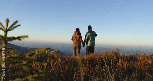 Tourist couple walk beautiful mountain valley. Female traveler with African American man come to admire awesome landscape. Greenery sways by strong wind. Awesome view of nature scenery. Slow motion.