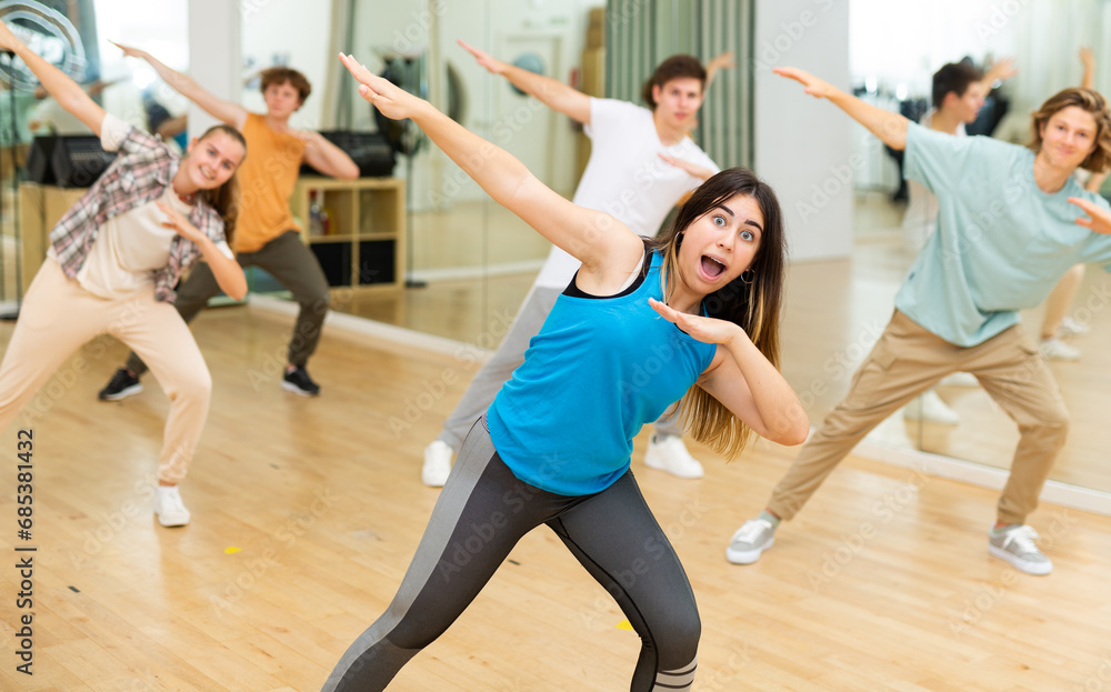 Group of active teens rehearsing modern dance in studio.