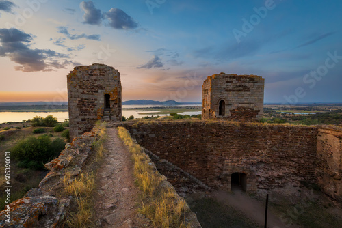 Mourao castle towers and wall at sunset with alqueva dam in Alentejo, Portugal photo