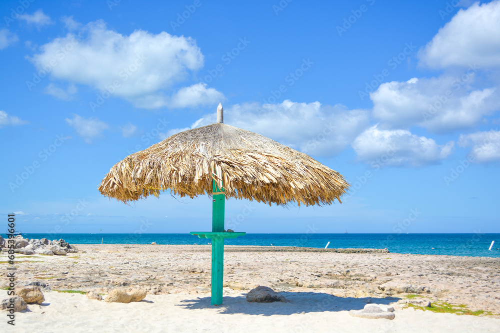 Thatched hut on a stretch of beach in Aruba overlooking the Caribbean Sea. Beautiful Caribbean summer seascape scene. Space for text. 