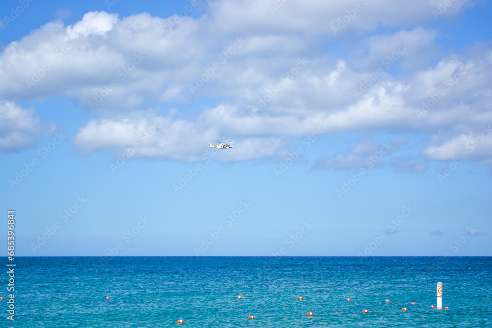 A  helicopter in the blue sky above beautiful Caribbean sea. Space for text. 