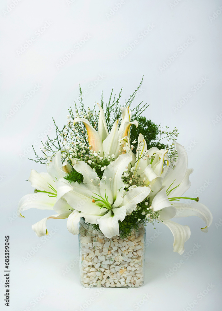 A vertical image of a beautiful bouquet of white lilies in a glass vase on isolated on white background