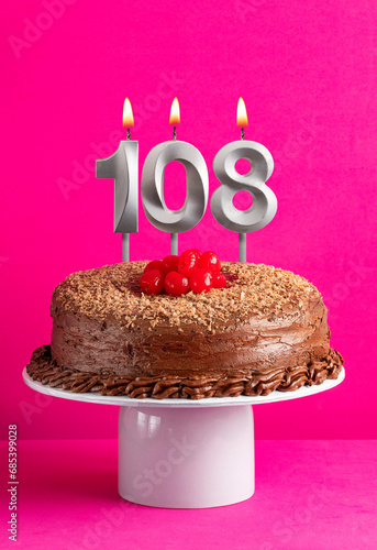 Number 108 candle - Chocolate cake on pink background