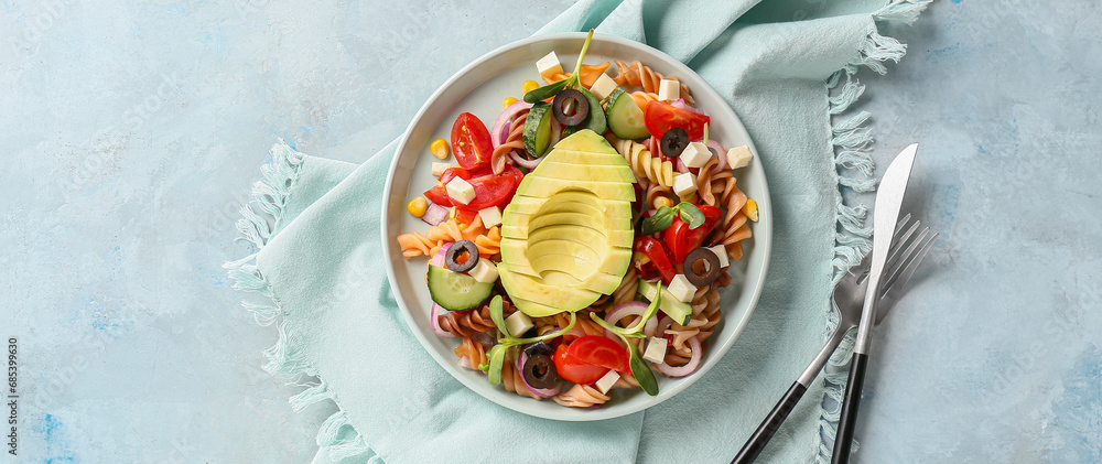 Plate with tasty pasta salad on blue background