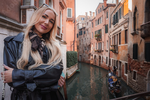 A woman in a leather jacket poses on a bridge in Venice, Italy, enjoying the city's canals. The overall vibe is casual and relaxed.
