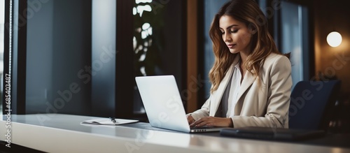 Portrait of Successful Businesswoman Sitting at Her Desk with Laptop in Office