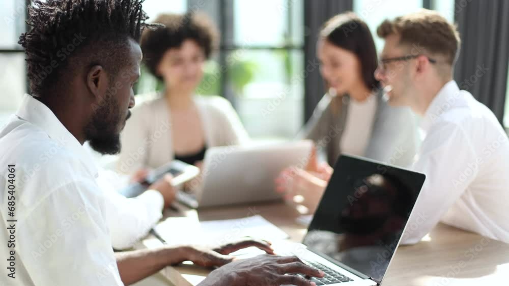 smiling African American business man with executives working in background smiling African American business man with executives working in background