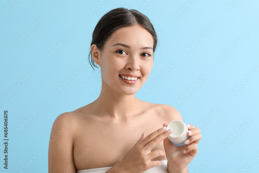 Beautiful Asian woman with jar of cream on blue background, closeup Beautiful Asian woman with jar of cream on blue background, closeup