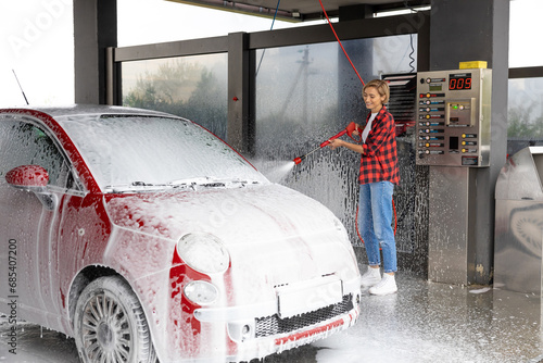 Woman working at the car wash and washing the car