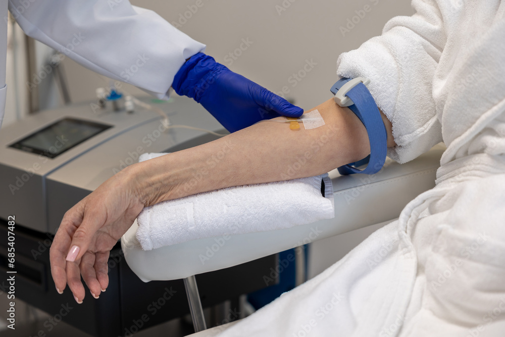 Woman receiving vitamin IV infusion drip in wellness center or beauty salon.