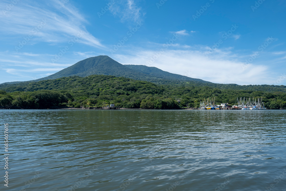 Coastline Seen From Afar with a Volcanic Mountain, Lush Vegetation Forest and a Small Marina with Boats with a Calm Ocean