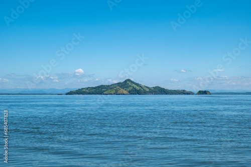 Obraz na płótnie Island Seen From Afar with Volcanic Hills with Patches of Deforestation for Grazing and Forest in Front of a Calm Ocean w salonie