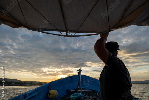 Obraz na płótnie Woman Captain Holds to the Roof of the Boat Prior to Arrival in the Port at Dusk w salonie