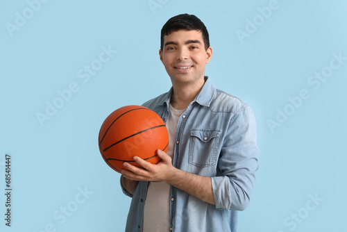 Happy young man with ball on blue background