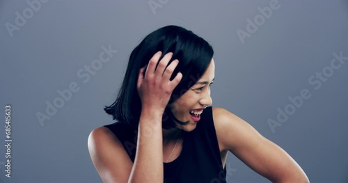 Asian, face and woman laugh in studio with funny joke, happiness or reaction to comedy. Happy, portrait and girl with comic, joy or lol emoji with humor and smile in grey background or mockup photo