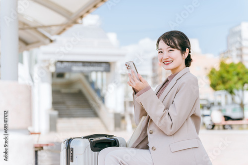 駅・空港から配車アプリでタクシー・レンタカーを呼ぶ女性（出張・レンタカー・旅行）  © buritora