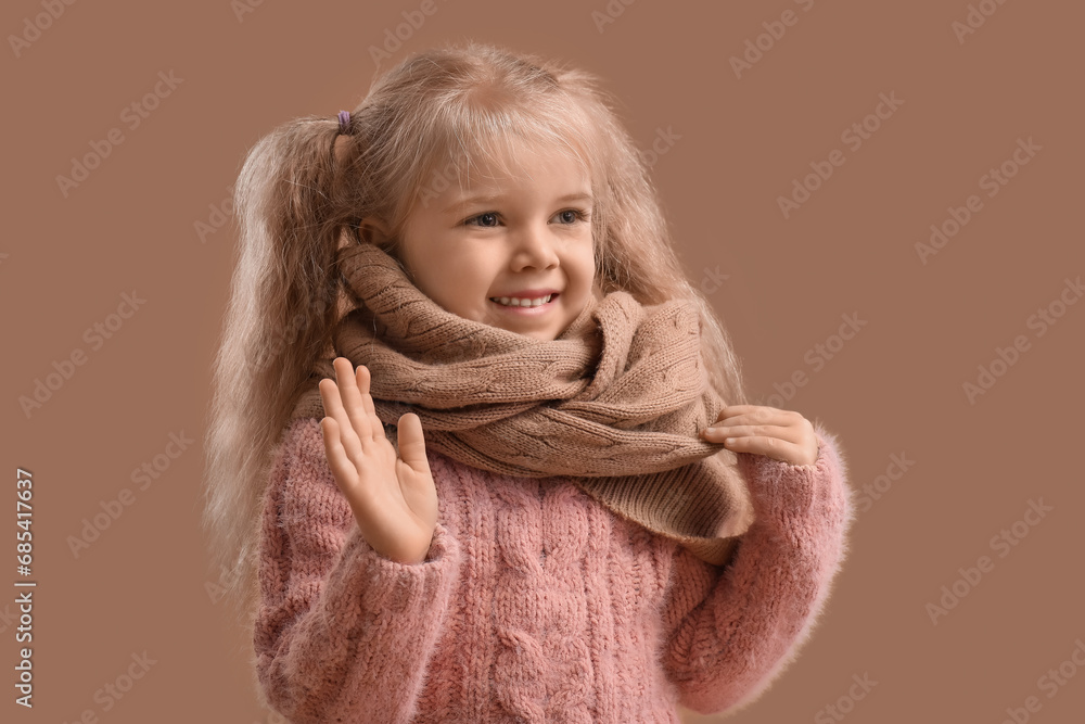 Cute little girl in knitted scarf on beige background Cute little girl in knitted scarf on beige background