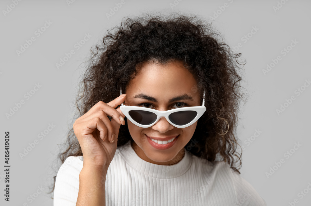 Stylish African-American woman in sunglasses on grey background, closeup Stylish African-American woman in sunglasses on grey background, closeup