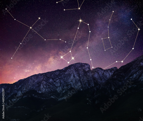 Different constellations in starry sky over mountains at night photo