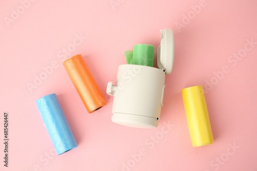 Dog waste bags and dispenser on pink background, flat lay