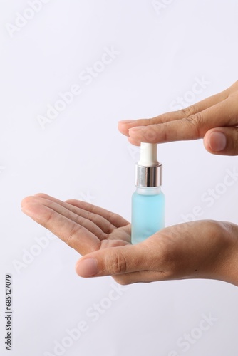 Woman with bottle of cosmetic serum on white background, closeup