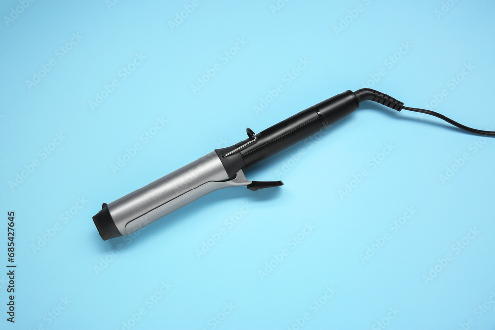 Hair styling appliance. One curling iron on light blue background, top view Hair styling appliance. One curling iron on light blue background, top view