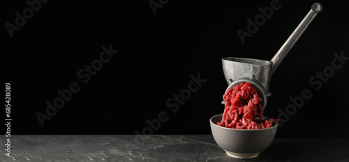 Mincing beef with manual meat grinder on grey table. Banner design with space for text photo