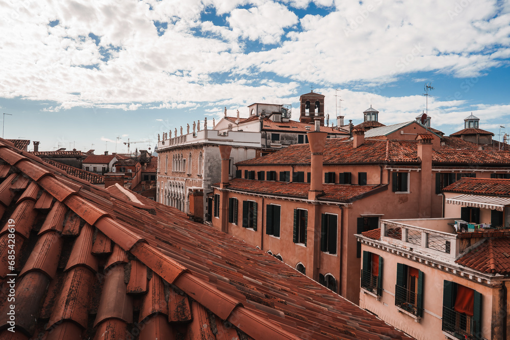 Cityscape of Venice, Italy with buildings and rooftops under a cloudy sky. Predominant colors are various shades of gray and brown, capturing the unique urban atmosphere of the city.