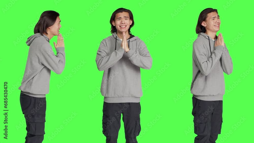 Person keeping hands in a prayer to ask Jesus for good luck, feeling religious and praying against greenscreen isolated template. Religious asian guy acting hopeful in studio. Person keeping hands in a prayer to ask Jesus for good luck, feeling religious and praying against greenscreen isolated template. Religious asian guy acting hopeful in studio.