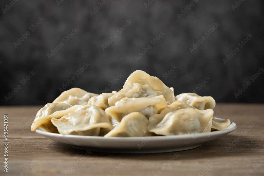 fresh boiled dumplings in plate on wooden background.
