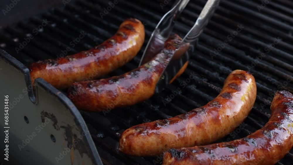 Grilled BBQ meat sausages on stainless grill with fire flames close up. Food and cuisine concept. Grilled BBQ meat sausages on stainless grill with fire flames close up. Food and cuisine concept.