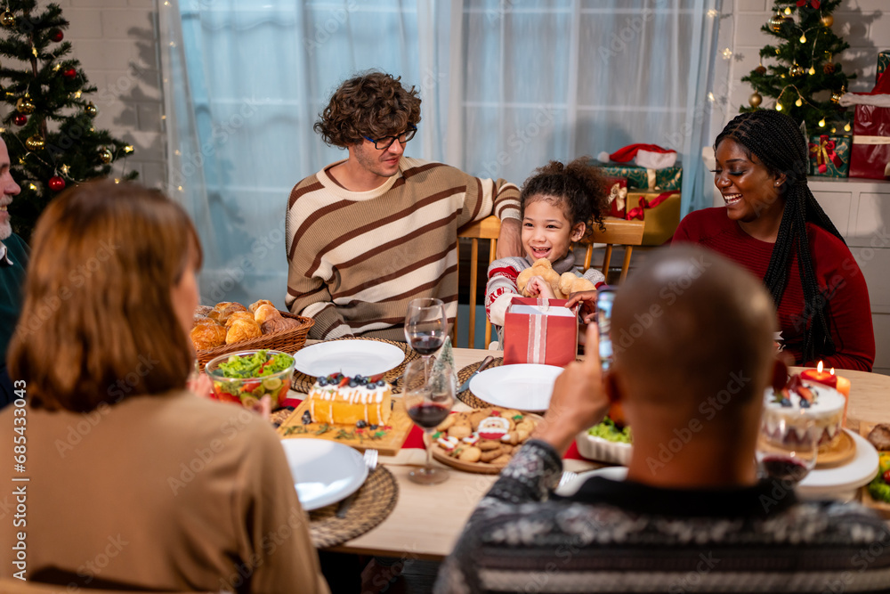 Multi-ethnic family giving gift box to daughter during Christmas party. Multi-ethnic family giving gift box to daughter during Christmas party.
