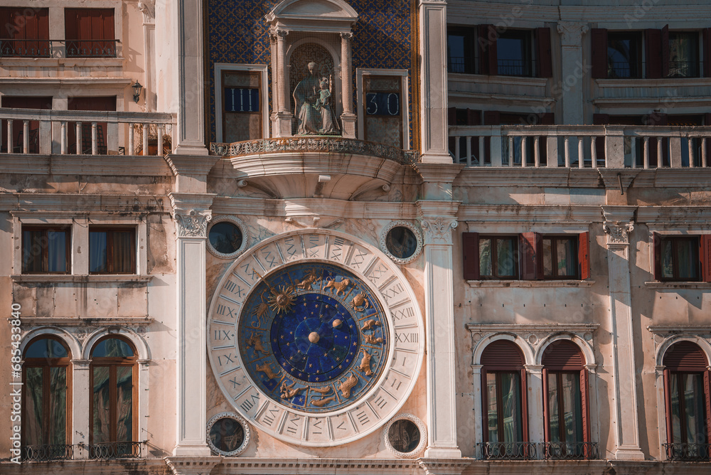 A stunning blue clock tower on a white, ornate building in Venice, Italy. The architectural style appears to be from the Renaissance period, adding to the historical charm of the city.