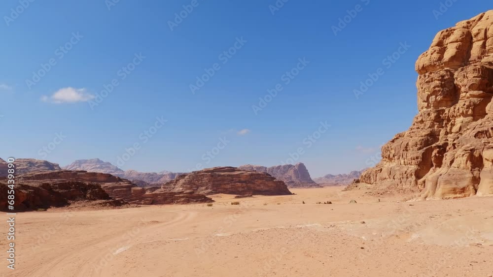 Sweeping view of Wadi Rum desert mountain valley region under blue sky Sweeping view of Wadi Rum desert mountain valley region under blue sky