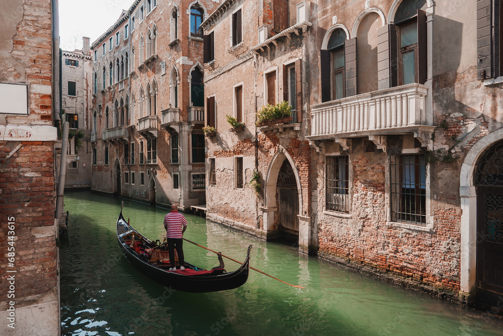 A serene gondola glides along a picturesque canal in Venice, Italy. The timeless image captures the essence of the city's romantic waterways and historic charm.