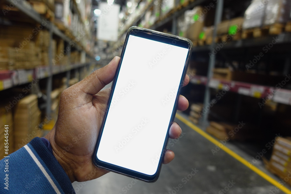 business owner holding phone mock up in warehouse. business owner holding phone mock up in warehouse.