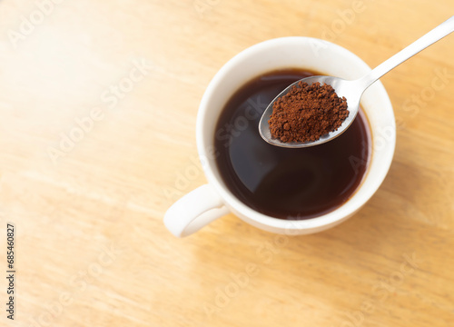 An image close-up top view or flat lay ground black coffee instant roasted on the spoon is a hot drink for beverage morning is a wood table background with copy space for text.