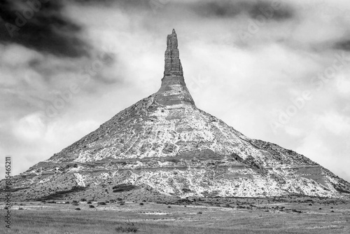 Snow-dusted winter landscape in black and white of Chimney Rock National Monument in Nebraska with cloudy sky.