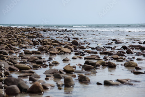 Rocks/stones on the beach during a daylight on the islands, Thailand.Background image of the beach with sea in the distance with pebble stones.