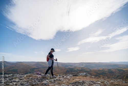 woman on mountain peak looking in beautiful mountain valley in autumn. Landscape with sporty young woman, blu sky in fall. Hiking. Nature