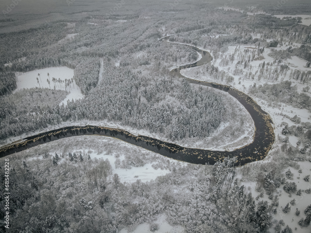 Aerial view of winter landscape with snow covered Forest and River. River Gauja