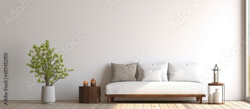 White ceiling and wall in living room, wooden box with fancy flowering plant by sofa and pillows, stand lamp by window, bed and washroom present. © AkuAku