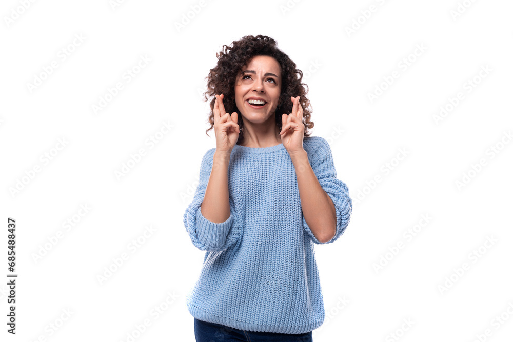 a young pretty lady with black curly hair dressed in a light blue sweater crossed her fingers in anticipation a young pretty lady with black curly hair dressed in a light blue sweater crossed her fingers in anticipation