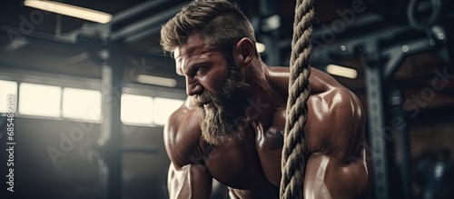 Strong man exercising with a rope in a functional fitness gym.